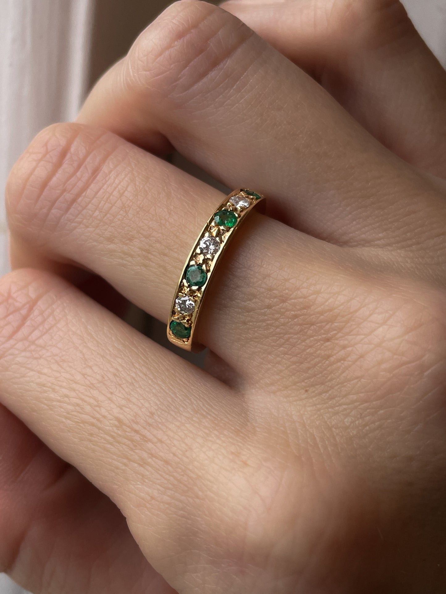 A vintage 1970s emerald and diamond half eternity ring on 18ct gold